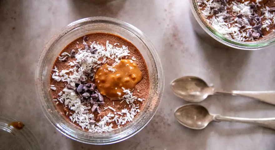 Chokladpudding med kokos och kakaonibs, en härlig proteinrik frukost. Två skedar ligger bredvid.
