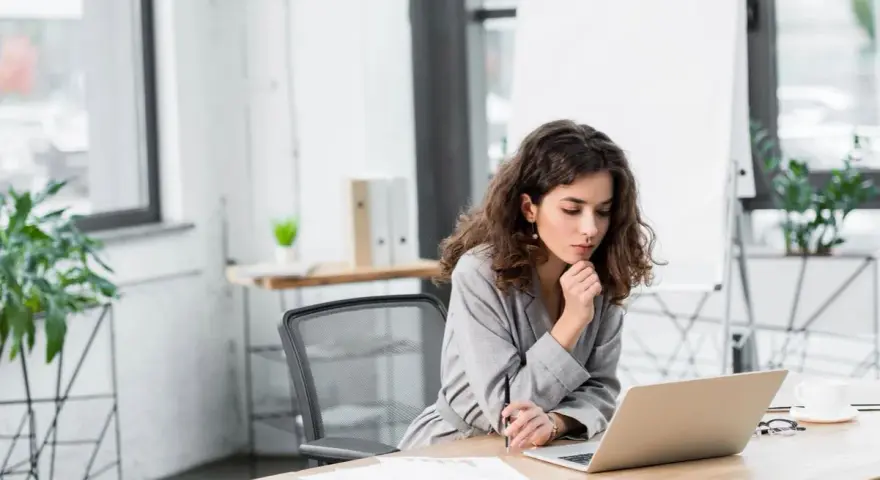 Kobieta analizuje przykładowy rachunek za prąd na laptopie w biurze.
