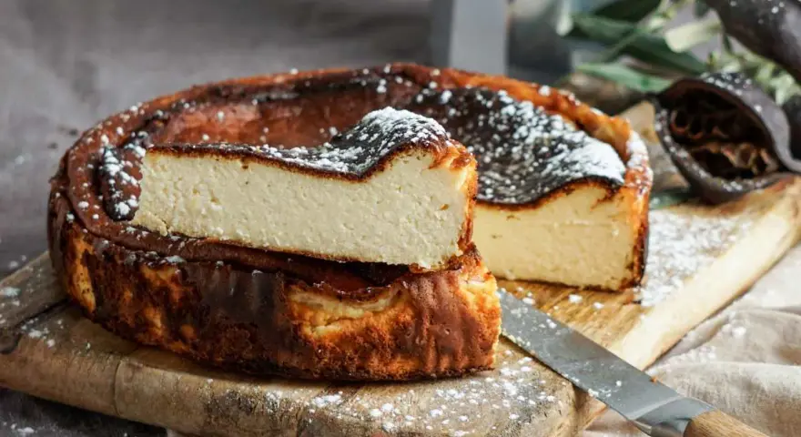 Tarta de queso La Viña, receta auténtica con su interior cremoso y exterior caramelizado, espolvoreada con azúcar glas.