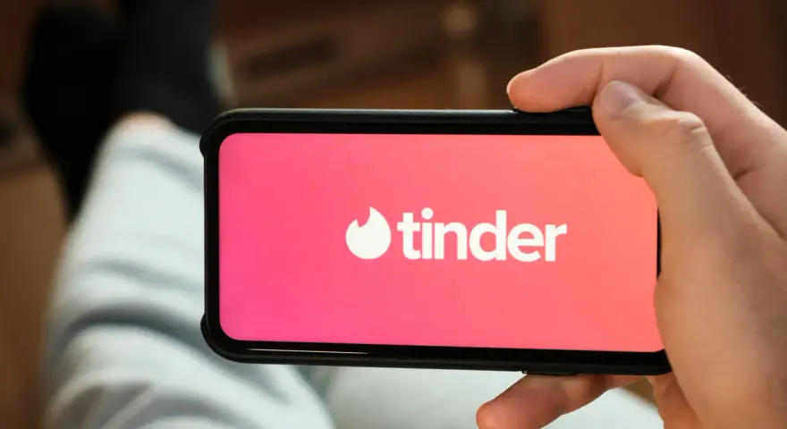 Dłoń trzyma smartfon z otwartą aplikacją do randkowania Tinder.