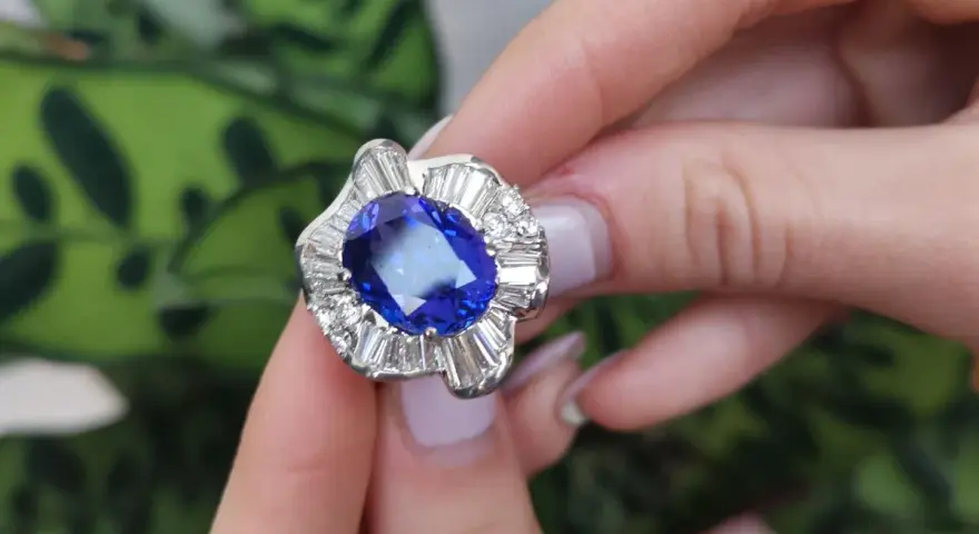 Anello con una preziosa pietra azzurra al centro, circondata da diamanti a baguette e taglio brillante.