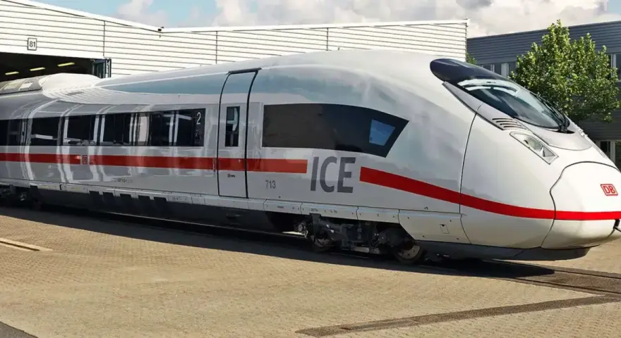 Biały pociąg ICE 5 z czerwonym pasem stoi na torach przed budynkiem.