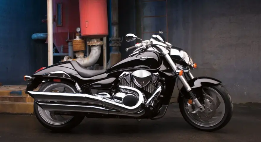 Czarny Suzuki Boulevard 1800 lśni w blasku przemysłowego otoczenia. Potężny silnik i chromowane detale przyciągają wzrok.