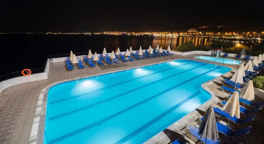 Basen hotelowy nocą, z widokiem na oświetlone miasto na horyzoncie. Idealne miejsce na relaks, jak sugerują pozytywne opinie o horizon beach.