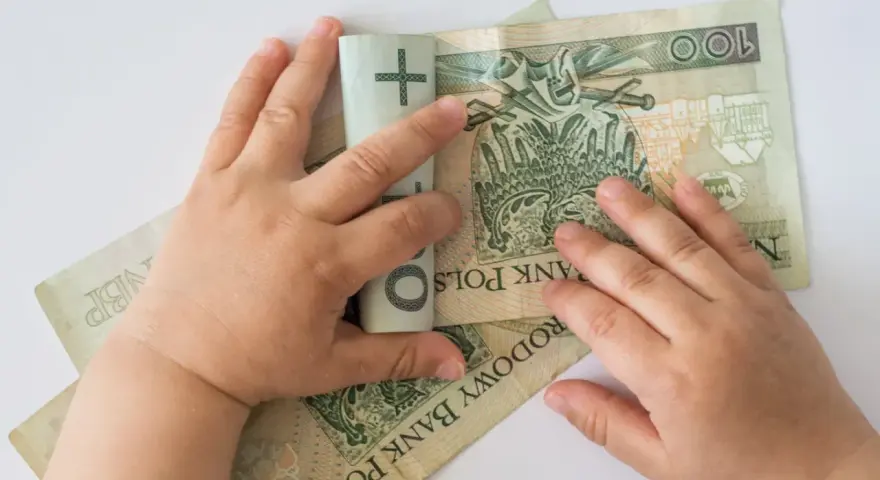 Dziecko bawi się banknotami 100 zł. Czy to już 12 tys na dziecko?
