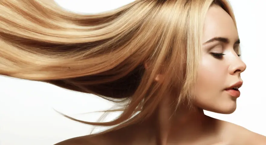 Blond włosy falujące na wietrze, lśniące jak po płukance octowej. Delikatny profil kobiety z zamkniętymi oczami.