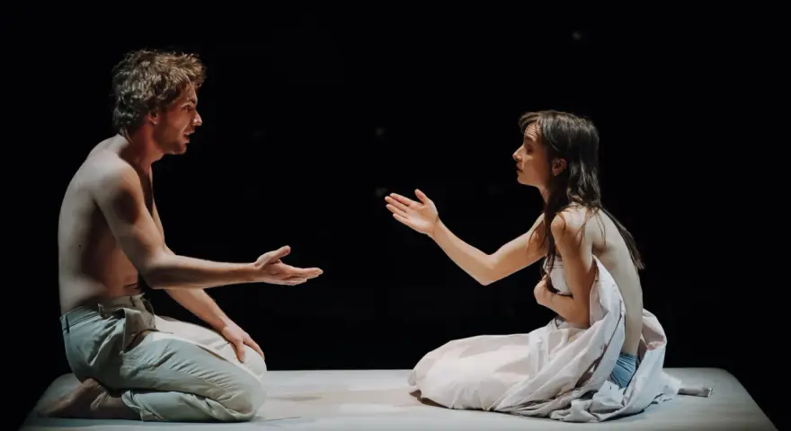Aktorzy na scenie Teatru Narodowego, w intymnym geście, jakby dzielili się ostatnim tchnieniem.
