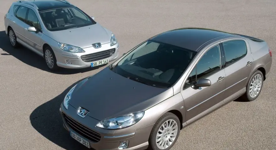 Dwa samochody Peugeot 407, sedan i kombi, na drodze. Wiele osób chwali sobie te modele, a opinie o Peugeot 407 są zazwyczaj pozytywne.