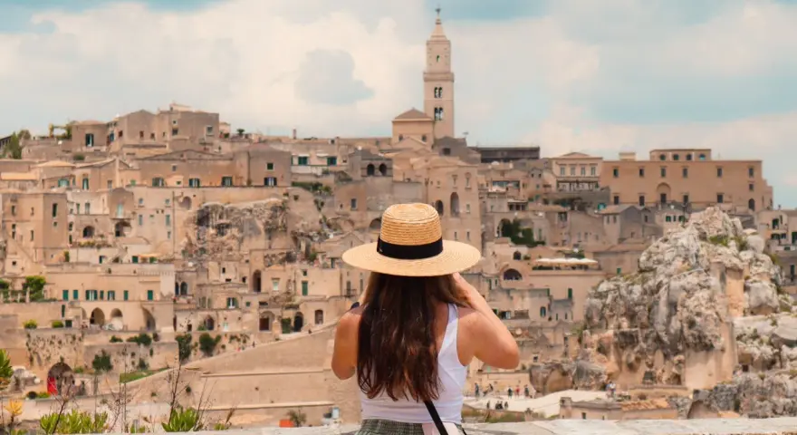 A woman in a straw hat captures the ancient city of Matera, a highlight of her southern tour of Italy.