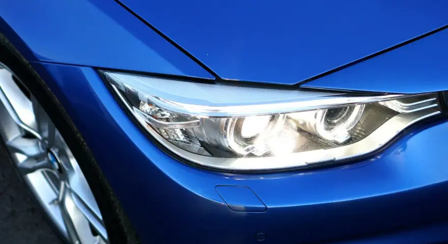 Blå BMW-strålkastare, redo för prewash. En del av en sportig bil med blanka fälgar.