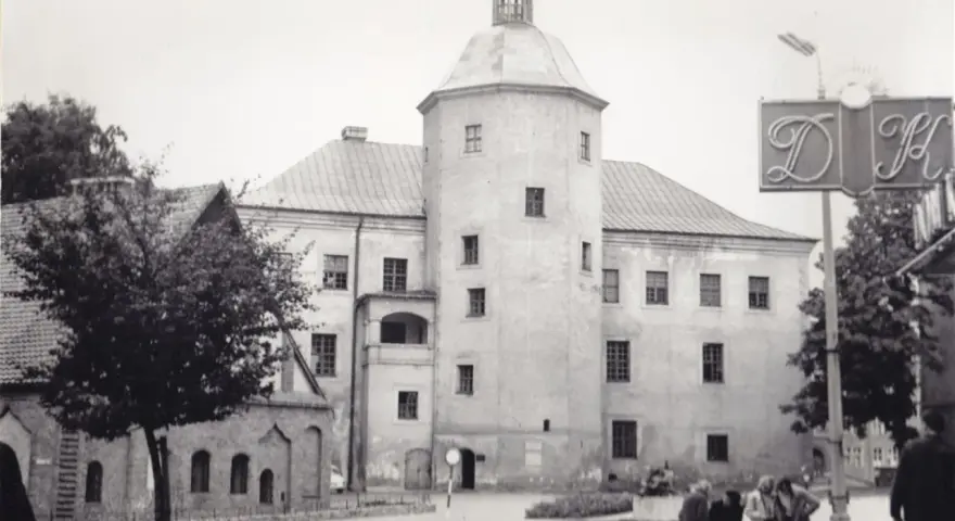 Zamek książąt pomorskich w Słupsku, z charakterystyczną wieżą i arkadowym balkonem, na tle miejskiego krajobrazu.