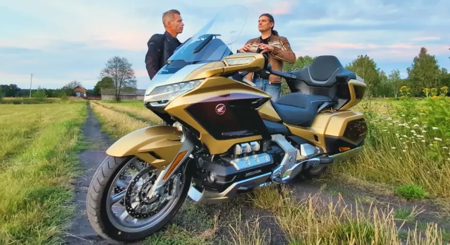 Złoty Honda Goldwing 1800 na polnej drodze, dwaj mężczyźni dyskutują o jego wadach.