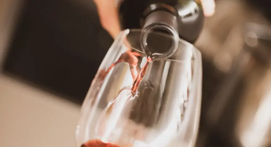 Czerwone wino nalewane do kieliszka. Czy otwarte wino się psuje? Zależy od sposobu przechowywania, ale świeżo otwarte smakuje najlepiej.