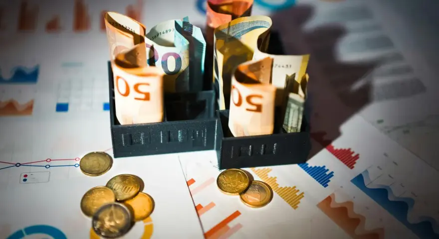 Billets d'euros enroulés dans des porte-billets, pièces et graphiques financiers. Illustration de la rémunération mandataire social.