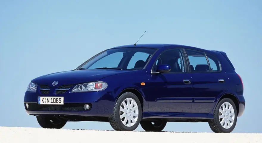 Granatowy Nissan Almera stoi na białym tle, z błękitnym niebem w tle.