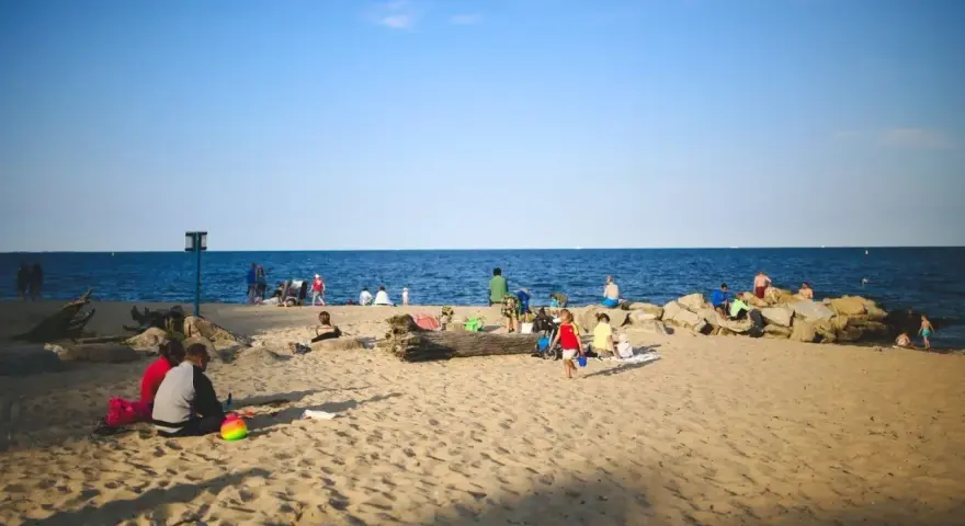Ludzie odpoczywają na plaży, ciesząc się słońcem i morzem. Widać, ile Szczecin ma do morza – bliskość natury i relaks.
