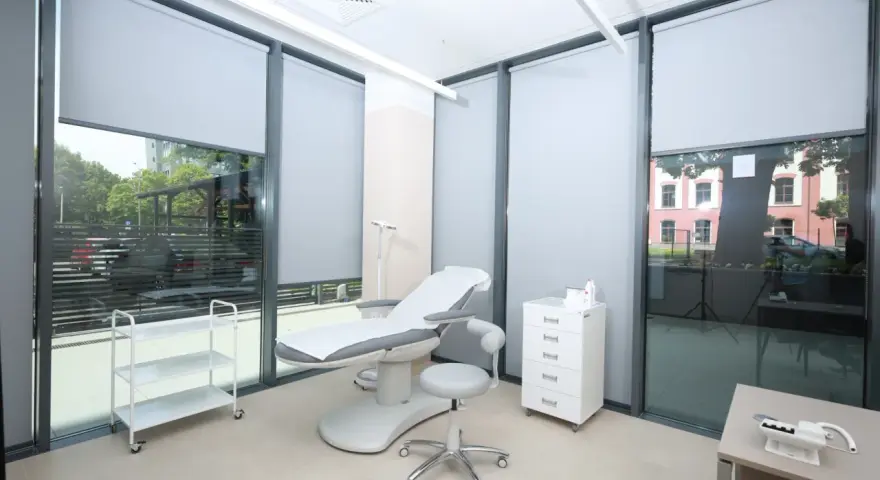 Gabinet dermatologiczny z fotelem zabiegowym, szafką i wózkiem.