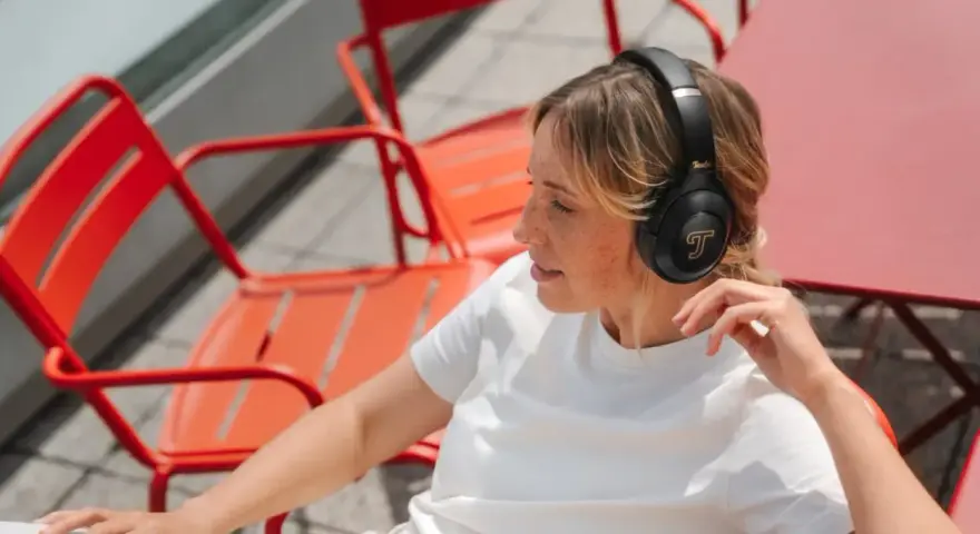 Femme aux taches de rousseur écoutant de la musique avec des écouteurs, un exemple de 85 dB pour une immersion sonore.