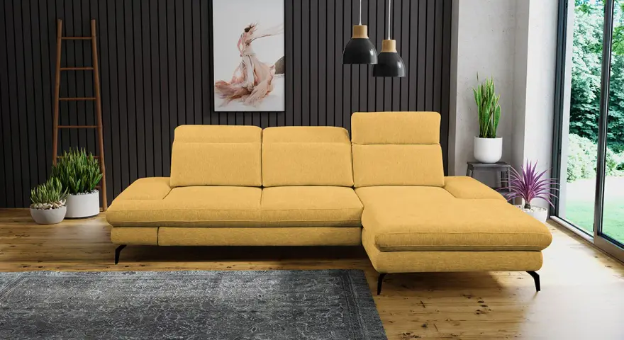 Un salon moderne avec un canapé jaune moutarde, un tapis gris foncé et des plantes vertes. Quelle couleur associer avec un canapé jaune moutarde ? Le gris est une excellente option.