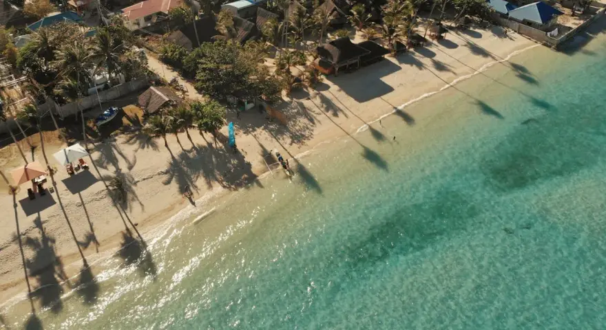 Tropikalna plaża z palmami i turkusową wodą. Idealne miejsce na wakacje, zastanawiasz się, ile trwa lot na Filipiny?
