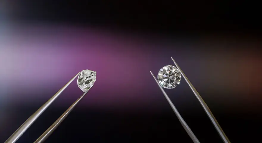 Dwa kamienie szlachetne w pęsecie: surowy brylant i oszlifowany diament.