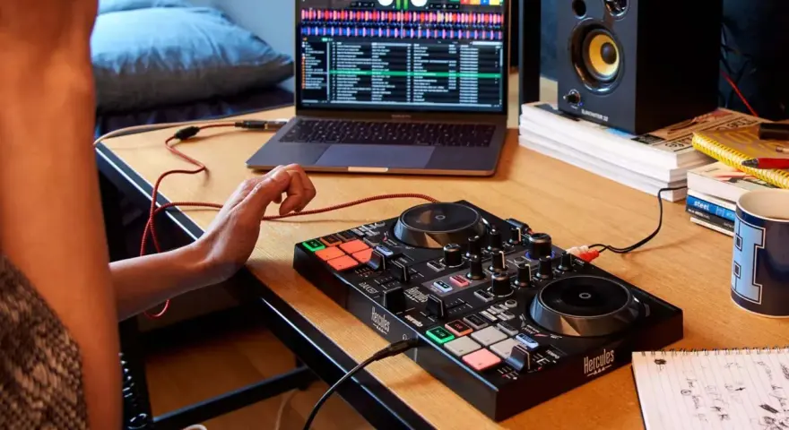 Osoba uczy się, jak zostać DJ-em, ćwicząc na kontrolerze DJ-skim i laptopie z oprogramowaniem muzycznym.