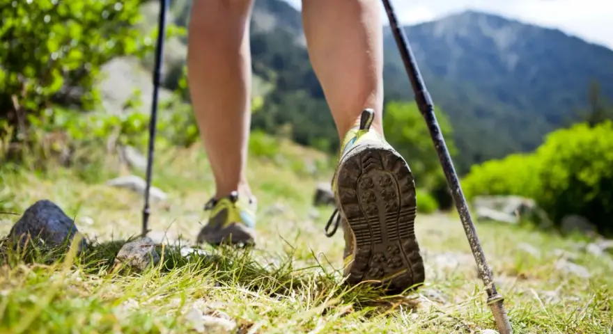 Nauka jak chodzić z kijkami to klucz do stabilności na górskim szlaku. Widok na nogi w butach trekkingowych i kijki wspierające marsz.