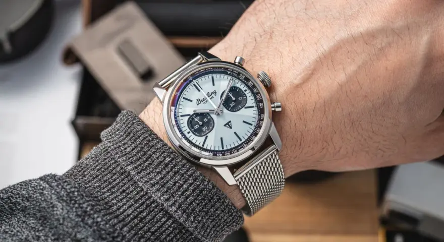 Mężczyzna prezentuje swój lśniący zegarek Breitling, gotowy do czyszczenia. Metalowa bransoleta i tarcza z chronografem błyszczą.