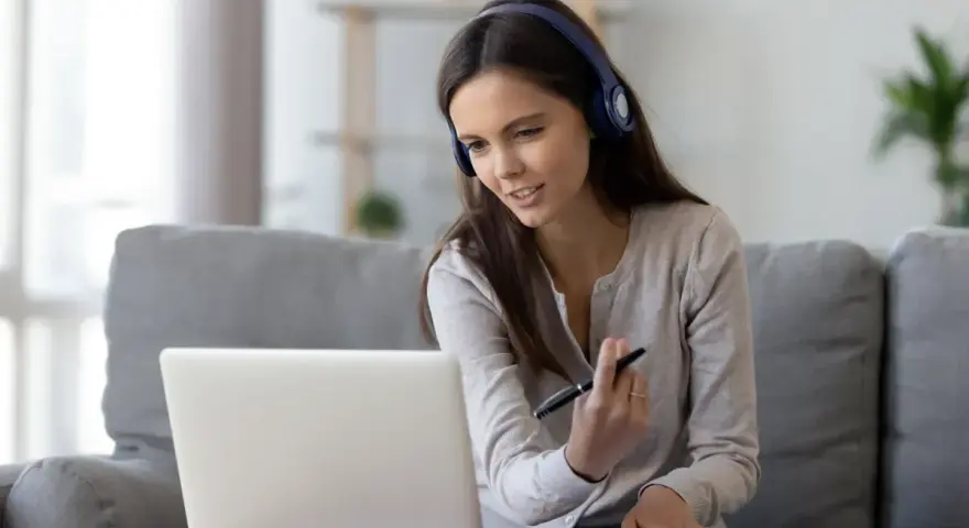 Kobieta w słuchawkach pracuje przy laptopie, tworząc komfortowy **home office**.