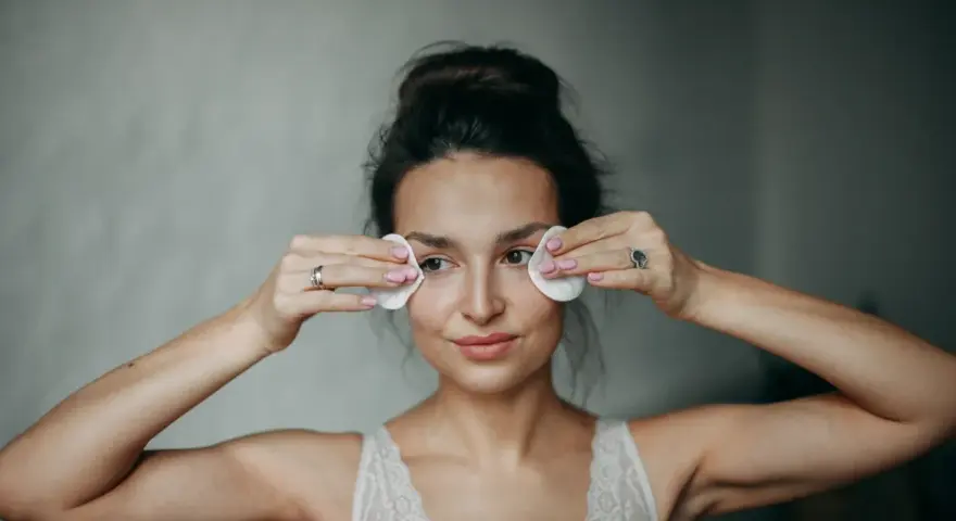 Kobieta wykonuje demakijaż oczu wacikami. Delikatne mycie twarzy olejem to jej rytuał.