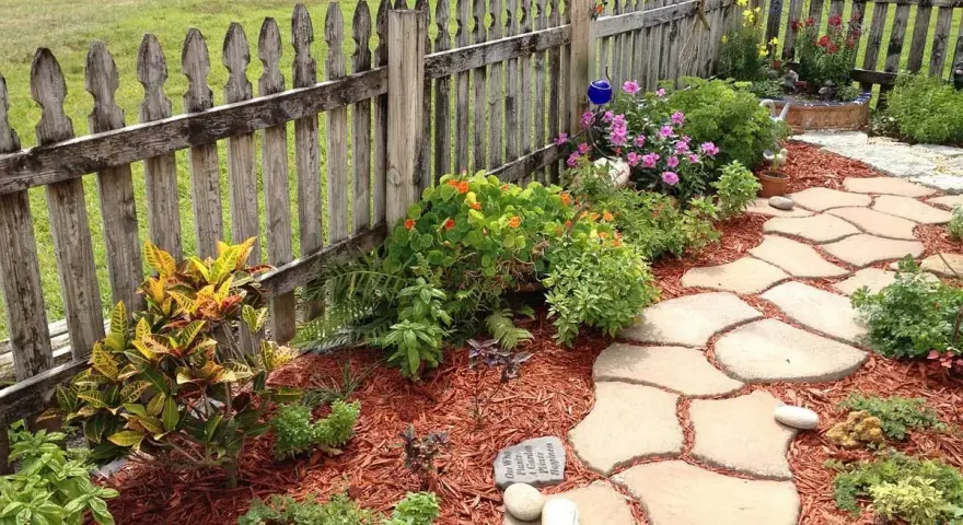 Natürliche Steinplatten formen einen geschwungenen Gartenweg, umgeben von bunten Blumen und grünen Pflanzen. Tolle Gartenweg Ideen für ein idyllisches Zuhause.