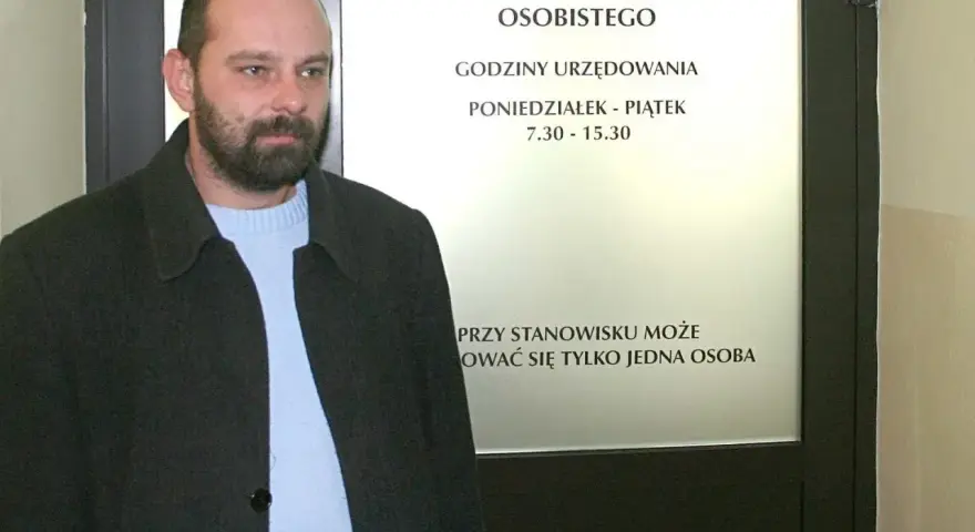 Mężczyzna z brodą przed urzędem, gdzie można złożyć wniosek o dowód. Sprawdź, ile kosztuje wyrobienie dowodu i godziny otwarcia.