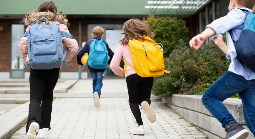 Niños corren con mochilas, ¡parece que ya empiezan las vacaciones de invierno!