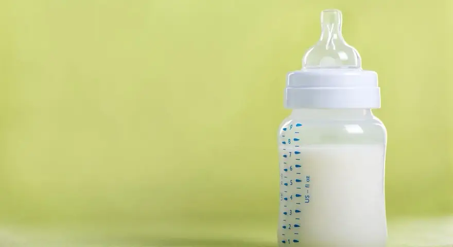 Gotowa do karmienia butelka do karmienia noworodka z mlekiem, na zielonym tle.