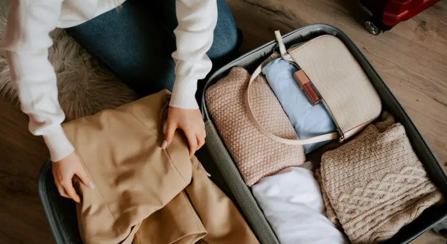 Pakowanie walizki. Zastanawiasz się, ile kosztuje dokupienie bagażu rejestrowanego Ryanair? W środku ubrania, torebka i kosmetyki.