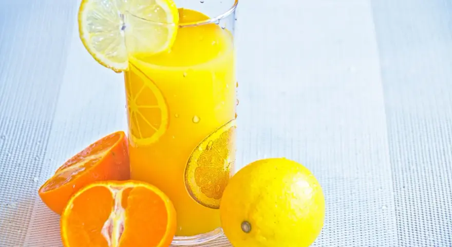 Succo d'arancia e limone, ricchi di vitamina C, in un bicchiere con fette di agrumi.