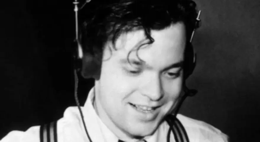 Orson Welles, giovane e sorridente con cuffie, un'immagine che evoca la sua genialità, ma non il suo orson welles causa morte.