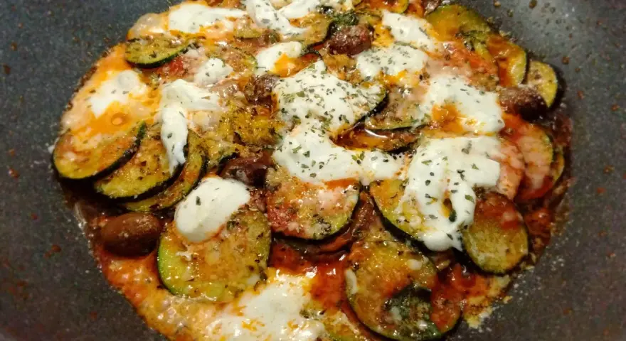 Zucchine alla pizzaiola in padella, con pomodoro, mozzarella filante e olive. Un piatto saporito e facile da preparare.