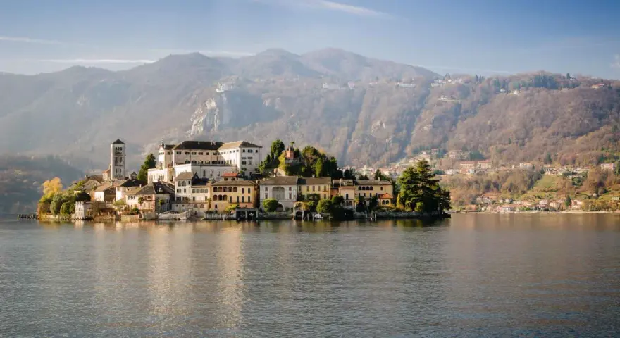 Isola di San Giulio, uno dei più bei posti da visitare in Piemonte, con il suo borgo antico sul lago d'Orta e le montagne sullo sfondo.