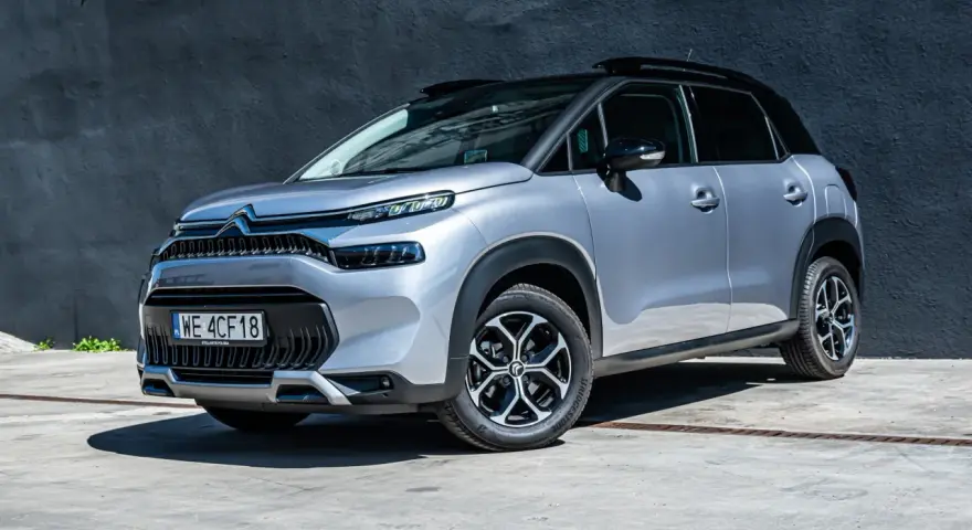 Srebrny Citroen C3 Aircross na tle ciemnej ściany. Wiele osób szuka **Citroen C3 Aircross opinie** przed zakupem.