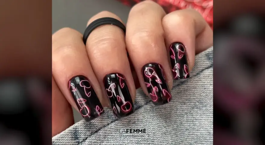 Unghie nere con un vivace disegno di ciliegie rosa neon. Un tocco di dolcezza estiva per le tue mani.