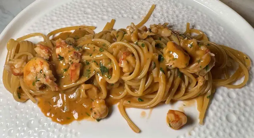 Spaghetti cremosi con mazzancolle e prezzemolo tritato, un piatto invitante e saporito.