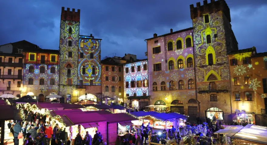 Un magico Arezzo tour: mercatini natalizi illuminati da proiezioni artistiche su torri e palazzi storici.