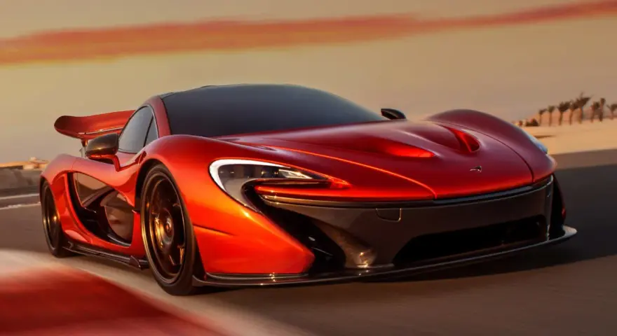 Czerwony McLaren P1 pędzi po pustynnej drodze o zachodzie słońca.