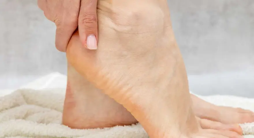Main d'une personne massant son talon pour hydrater ses pieds.