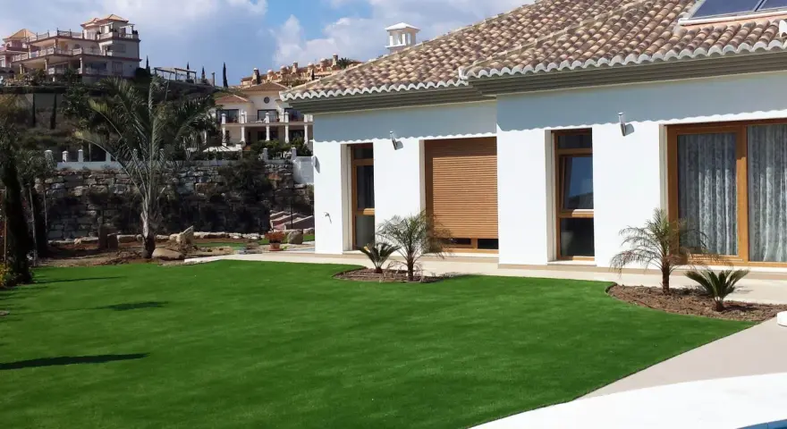 Modern villa con césped artificial en terrazas. Ideas para jardines de bajo mantenimiento y aspecto impecable.