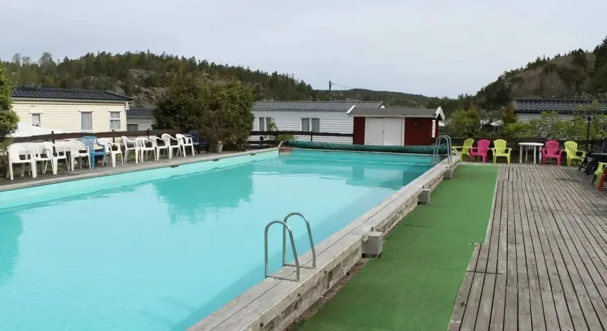 En stor pool med turkost vatten och solstolar i färgglada nyanser. En perfekt plats för avkoppling på camping Orust.