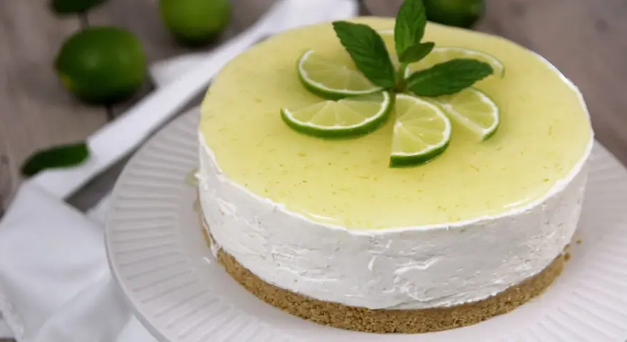 Cheesecake al mojito fresca e profumata, decorata con fettine di lime e menta.