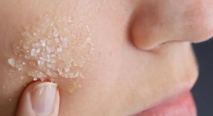 Dito, un dito applica un peeling acido glicolico a casa, con cristalli visibili sulla pelle.
