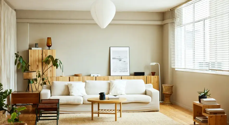 Salones nórdicos con sofá blanco, mesa de centro de madera y estanterías de pino. Luz natural entra por la ventana.